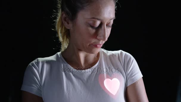 亮心投射到健康女性胸部的黑色背景 — 图库视频影像
