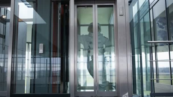 の近代的なオフィスビルのエレベーターに乗る宇宙飛行士 — ストック動画