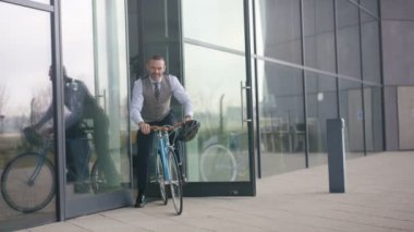 4k bir bisiklet üzerinde bina bürosundan çıkarken neşeli işadamı portresi