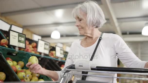 スーパーマーケットで食料品を購入するショッピングカートを持つ 年上の女性 — ストック動画