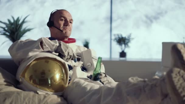 アパートでのんびり テレビを見て ビールを飲みながらの宇宙飛行士 — ストック動画