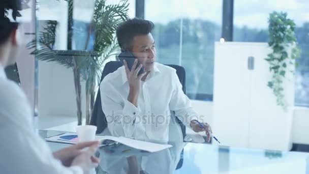 若いアジアのビジネスマネージャーが電話で話し 同僚と会う — ストック動画