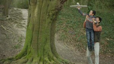 4 k mutlu baba ve oğul ormanda, küçük çocuk model uçak ile oynayan