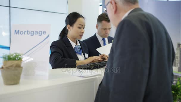 服务台的银行工作人员在计算机和协助客户方面工作 — 图库视频影像