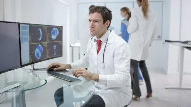 4k gülümseyen Doktor hastaya bakarak modern kliniğinde portresi inceden inceye gözden geçirmek üstünde bilgisayar