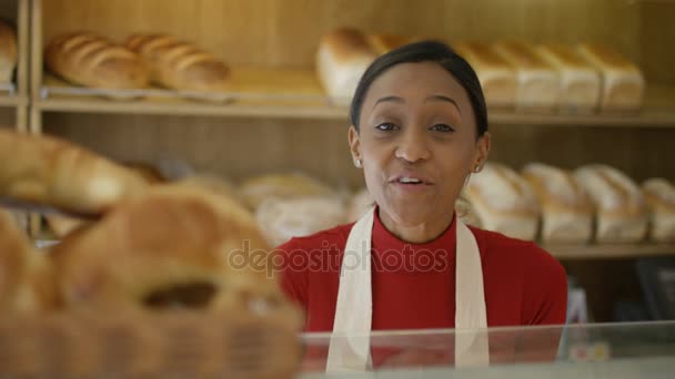 カウンターで顧客に役立つベーカリー ショップで のフレンドリーな労働者 — ストック動画