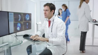 4k gülümseyen Doktor hastaya bakarak modern kliniğinde portresi inceden inceye gözden geçirmek üstünde bilgisayar