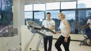 4k modern spor salonunda koşu bandı kullanarak kişisel antrenör kadınla