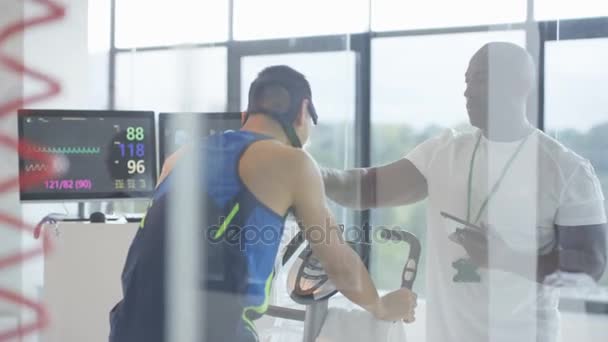 Sports Profesional Analizando Los Niveles Fitness Del Hombre Con Equipos — Vídeos de Stock