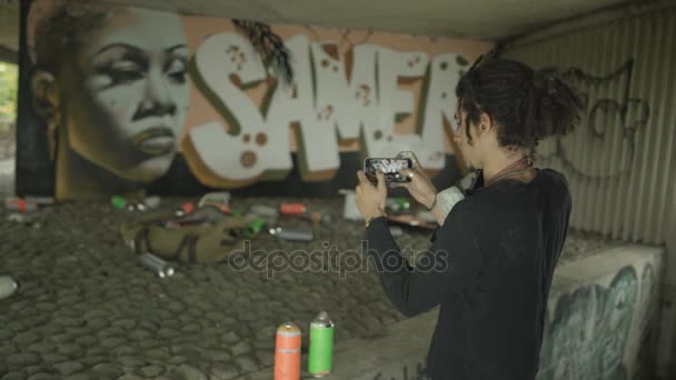 Masked Graffiti Artist Використовуючи Зображення Телефоні Копіювання Портрета Стіні Міста — стокове відео
