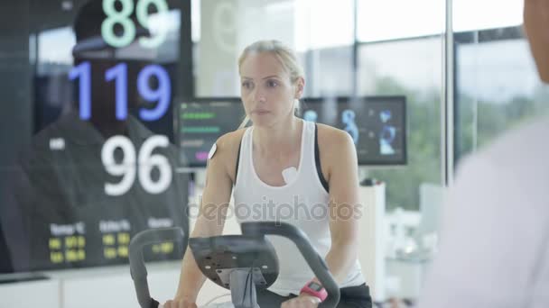 Αθλήτρια Άσκηση Ποδήλατο Που Ελέγχονται Και Παρακολουθούνται Από Αθλήματα Επιστήμονας — Αρχείο Βίντεο
