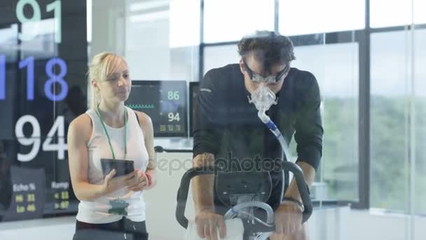 Male Athlete Exercise Bike Being Tested Monitored Sports Scientist — Stock Video