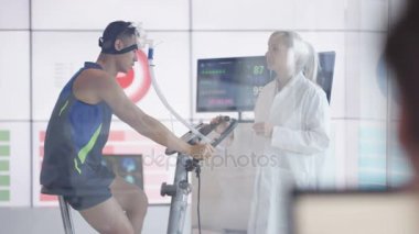 4 k spor bilim adamı beyaz ceket fitness egzersiz bisikleti üzerinde adamın değerlendirilmesi