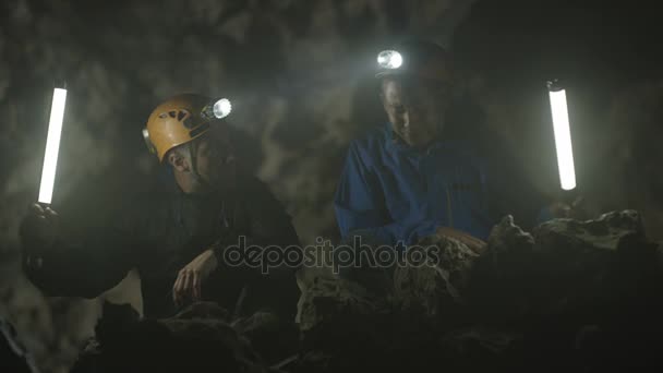 Spelunkers Вивчення Підземній Печері Обговорюючи Скельне Освіта — стокове відео