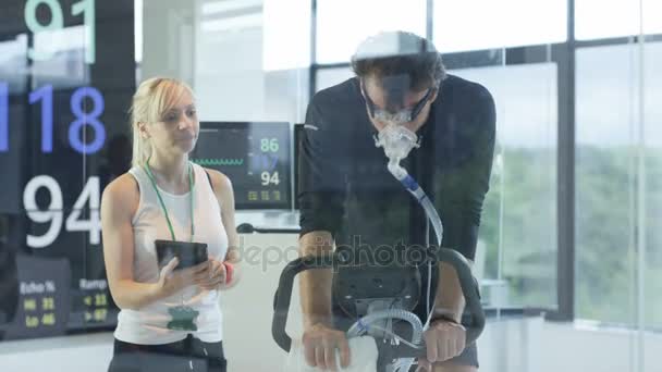 Male Athlete Exercise Bike Being Tested Monitored Sports Scientist — Stock Video