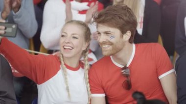 telefon ile selfie için poz spor olay kalabalığın içinde oturan 4k Copule