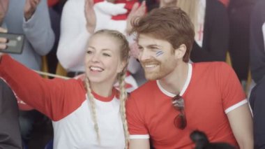 telefon ile selfie için poz spor olay kalabalığın içinde oturan 4k Copule