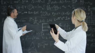 4 k bilim adamı ve tablet vasıl bakarak ve matematik formülleri tahtaya yazarak kadın 