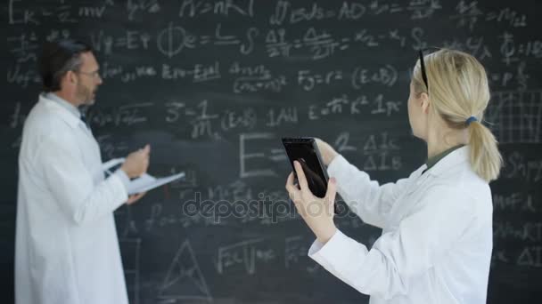 Science Man Woman Looking Tablet Writing Maths Formulas Blackboard — Stock Video