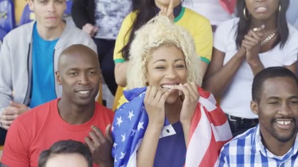 群众在体育赛事上欢呼 年轻女子手持美国国旗 — 图库视频影像