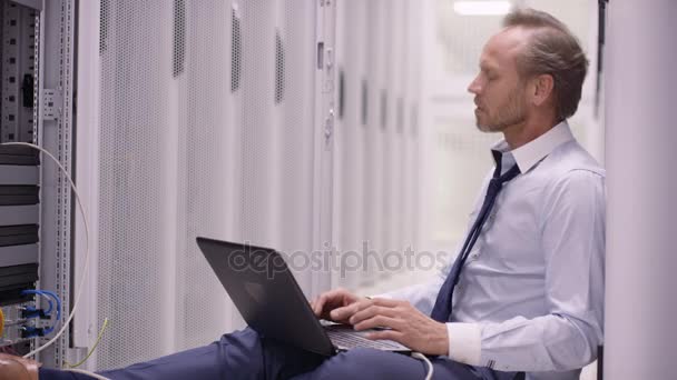 Stressed Computer Engineer Sitting Floor Working Laptop Checking Servers Data — Stock Video