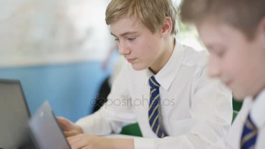 4K Young Boys bilgisayar çalışıyor, okulda birbirlerine yardım ediyorlar. 