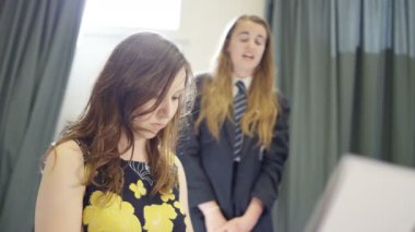 4K Teen girl singing and teacher playing keyboard in school music lesson 