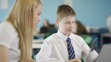 4k. Genç bir çocuk ve kız laptopa bakıyor, okulda birbirlerine yardım ediyorlar.