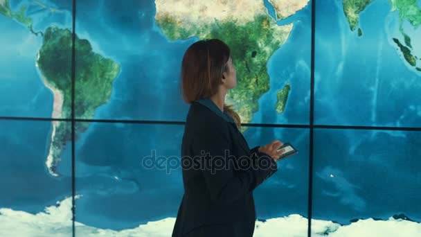 Geschäftsfrau Mit Tablet Schaut Auf Große Weltkarte Grafik Auf Videowand — Stockvideo