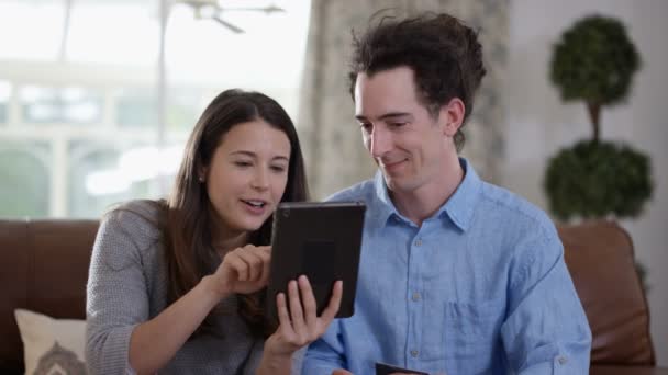 の陽気なカップル タブレットと自宅のオンライン ショッピングのクレジット カード — ストック動画