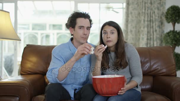 テレビを見ると画面上のアクションに反応して 食べるポップコーンをカップルします — ストック動画