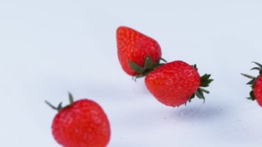 4 k taze kırmızı çilek beyaz bir yüzeye düşen ağır çekimde kapat