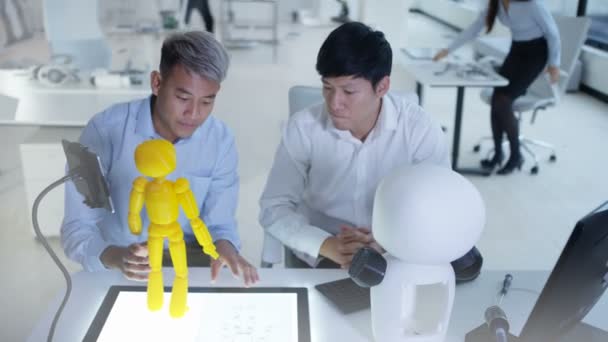 Ingénieurs en électronique asiatiques 4K travaillant en laboratoire avec un prototype de robot 