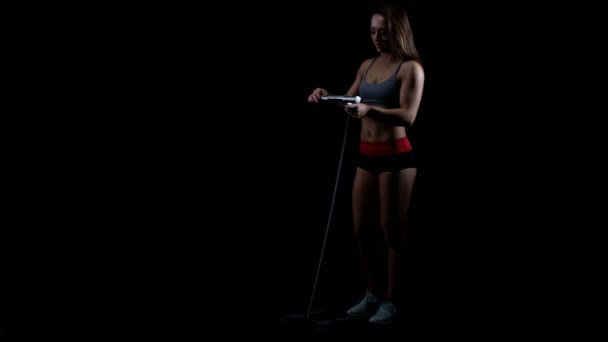 Passar Ung Kvinna Med Gymutrustning Mot Svart Bakgrund — Stockvideo