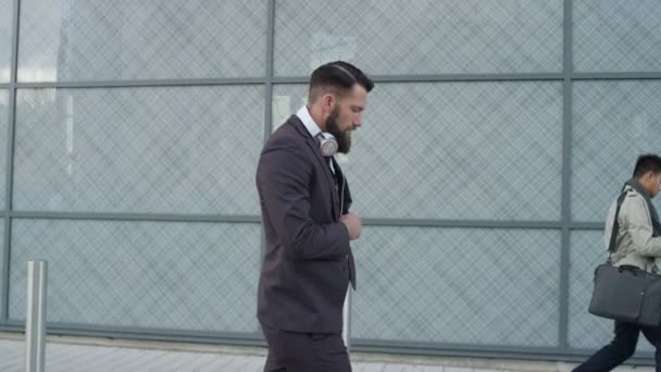 当他走路上班时 背胡子的商人戴上耳机 — 图库视频影像