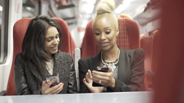 两位有吸引力的年轻女性在火车旅行中看智能手机 — 图库视频影像