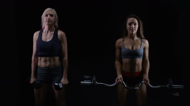 Twee Fit Jonge Vrouwen Trainen Met Gewichten Tegen Een Zwarte — Stockvideo