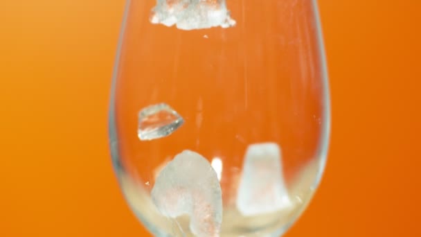 Crushed Ice Fallen Ein Glas Auf Orangefarbenem Hintergrund Nahaufnahme Zeitlupe — Stockvideo
