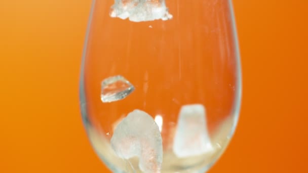 Hielo Triturado Caído Vaso Sobre Fondo Naranja Cerca Cámara Lenta — Vídeos de Stock