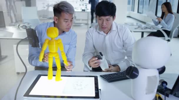 Ingénieurs en électronique asiatiques 4K travaillant en laboratoire avec un prototype de robot 