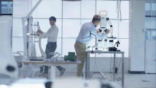 Ingénieurs techniques 4K travaillant sur la construction d'un robot automatisé dans un laboratoire moderne 