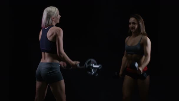 Zwei Fitte Junge Frauen Trainieren Mit Gewichten Vor Schwarzem Hintergrund — Stockvideo
