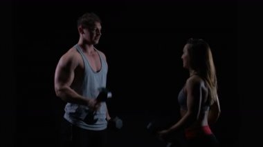 4 k uygun genç adam ve siyah bir arka plan karşı ağırlıklar ile çalışan kadın