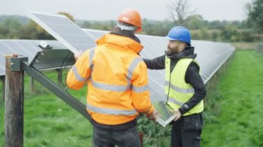 Güneş enerjisi fabrikasında çalışan 4 k teknisyenleri muayene için bir panelini çıkarma