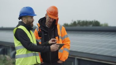 Güneş enerjisi tesisi işlemleri tartışırken bilgisayar tablet ile 4 k teknisyenleri