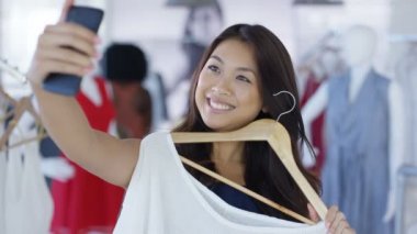 Müşteri aynaya bakarak ve fotoğrafta smartphone ile giyim mağazası. Arka planda alışveriş diğer müşteriler ile Mirror's pov görüldü.