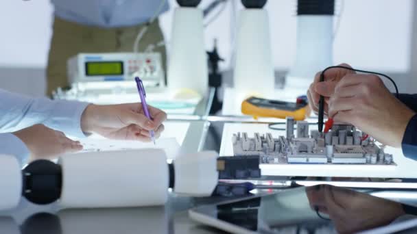 Équipe de conception technique 4K collaborant à la construction d'un robot dans un laboratoire moderne 