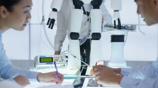 Équipe de conception technique 4K collaborant à la construction d'un robot dans un laboratoire moderne 