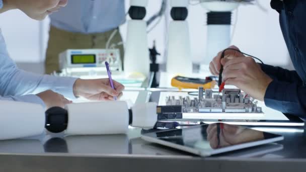 Équipe de conception technique 4K collaborant à la construction d'un robot dans un laboratoire moderne 