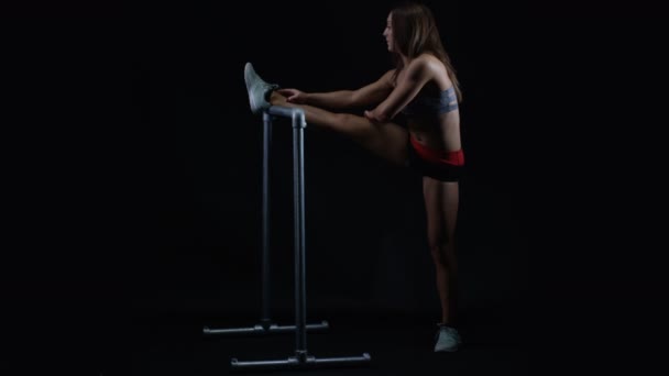 Fitte Junge Frau Streckt Ihre Beinmuskeln Vor Schwarzem Hintergrund Aus — Stockvideo